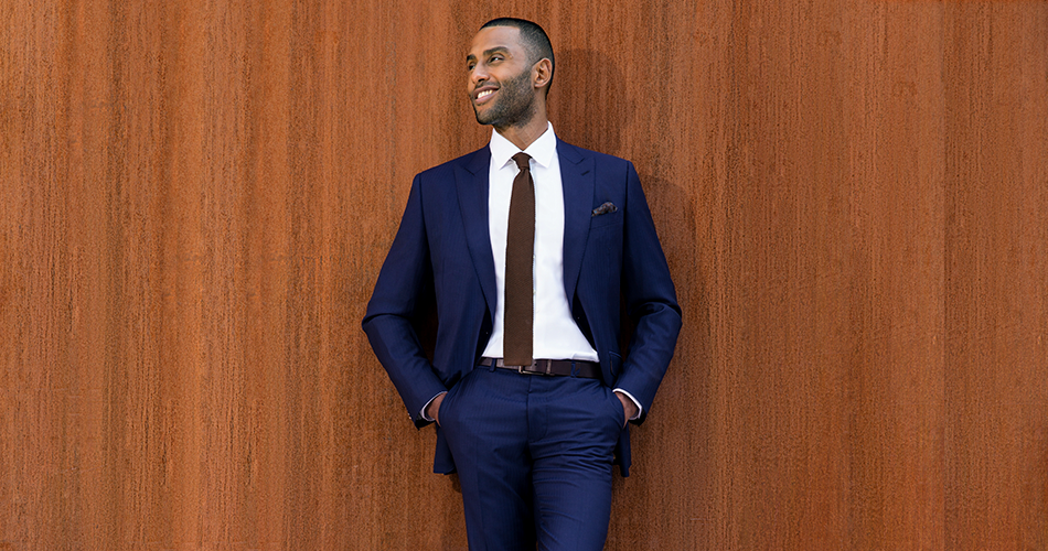 man in navy blue power suit against wooden wall